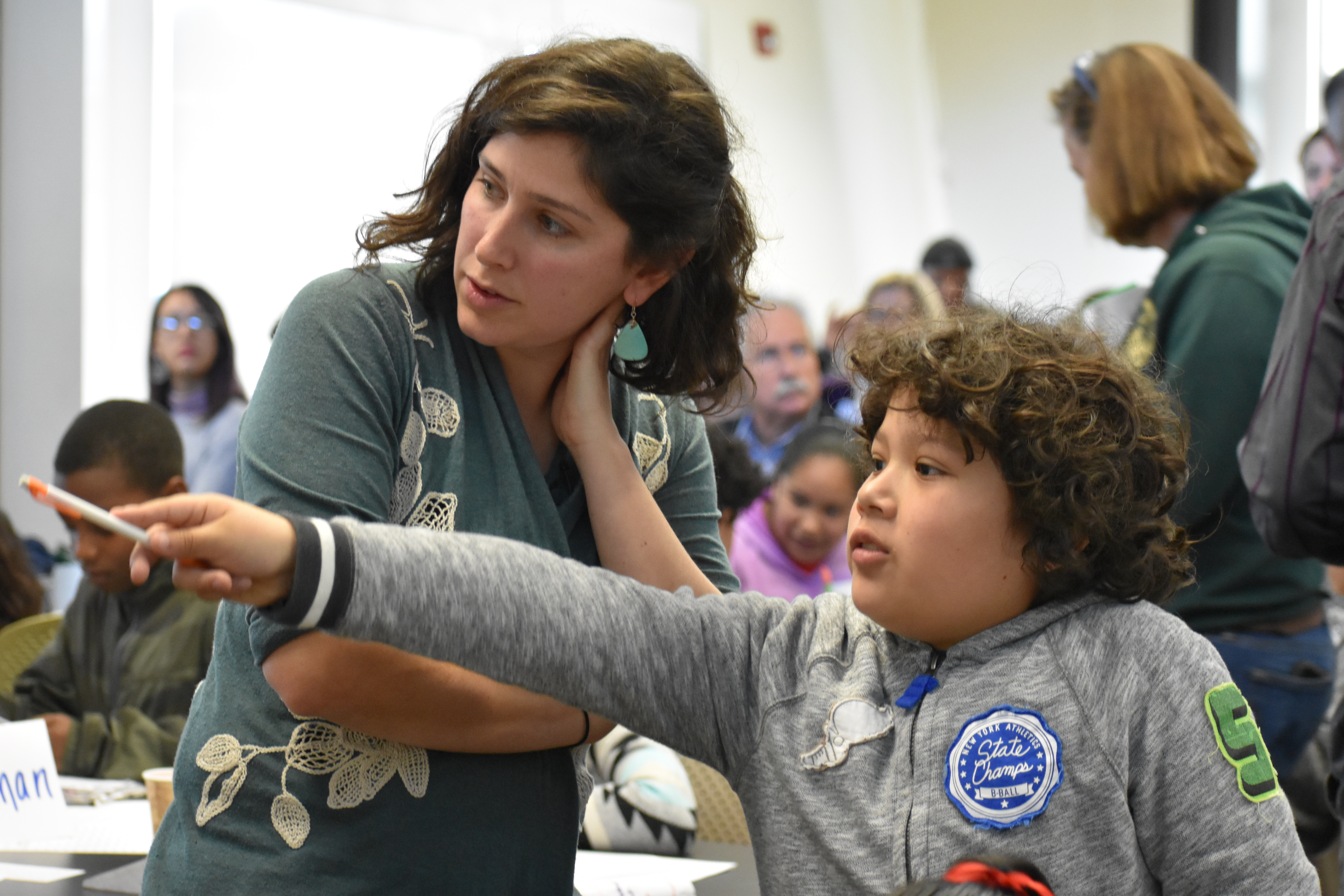 Boy pointing and teacher watching An elementary-age male student points while his female teacher stands beside him and observes