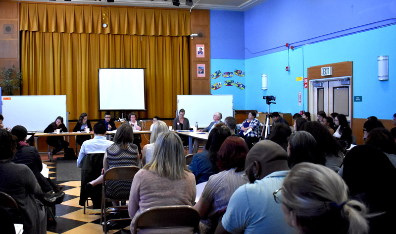 An elementary-age male student points while his female teacher stands beside him and observes