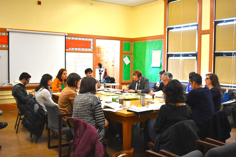 An elementary-age male student points while his female teacher stands beside him and observes