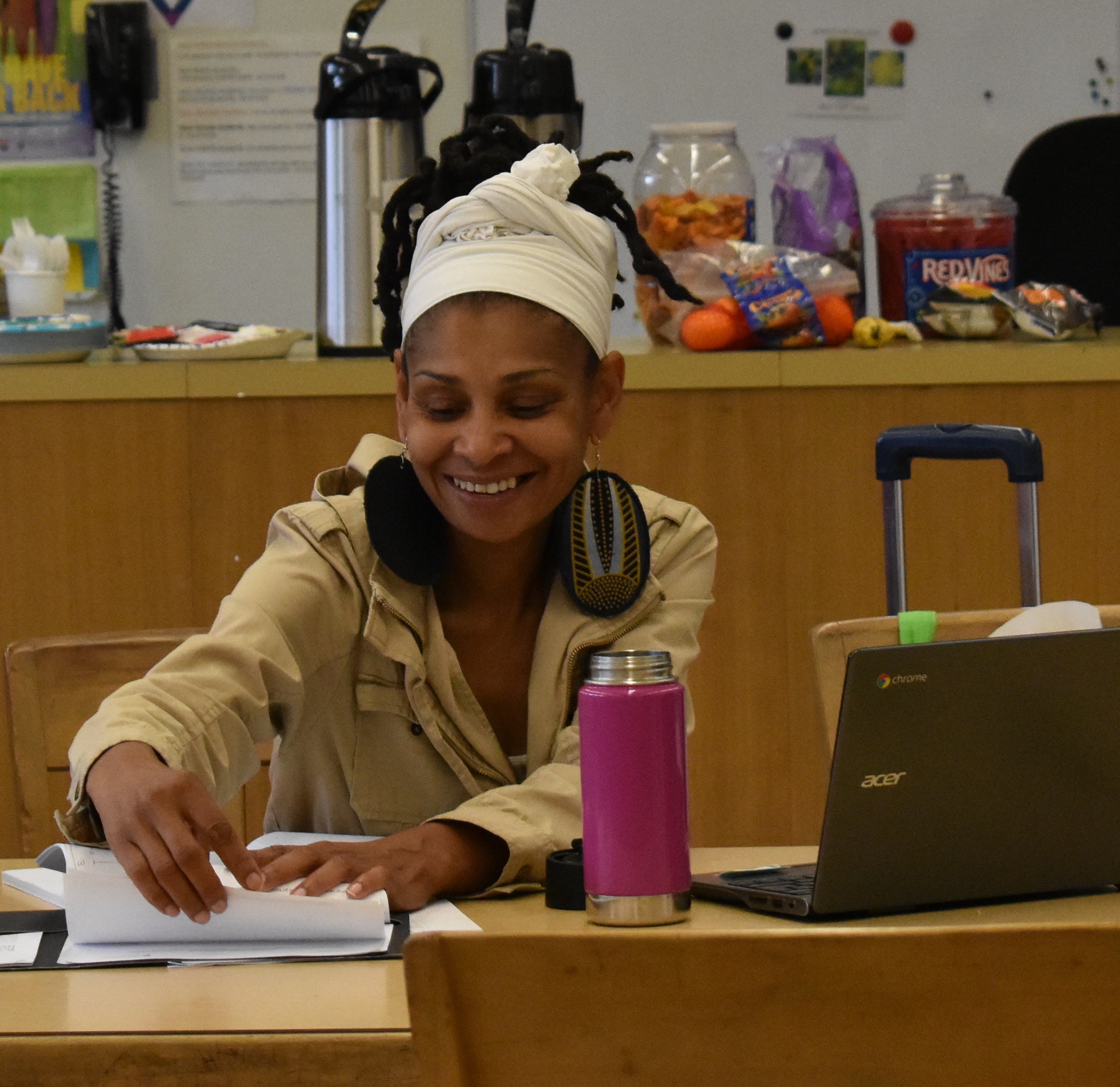 An elementary-age male student points while his female teacher stands beside him and observes