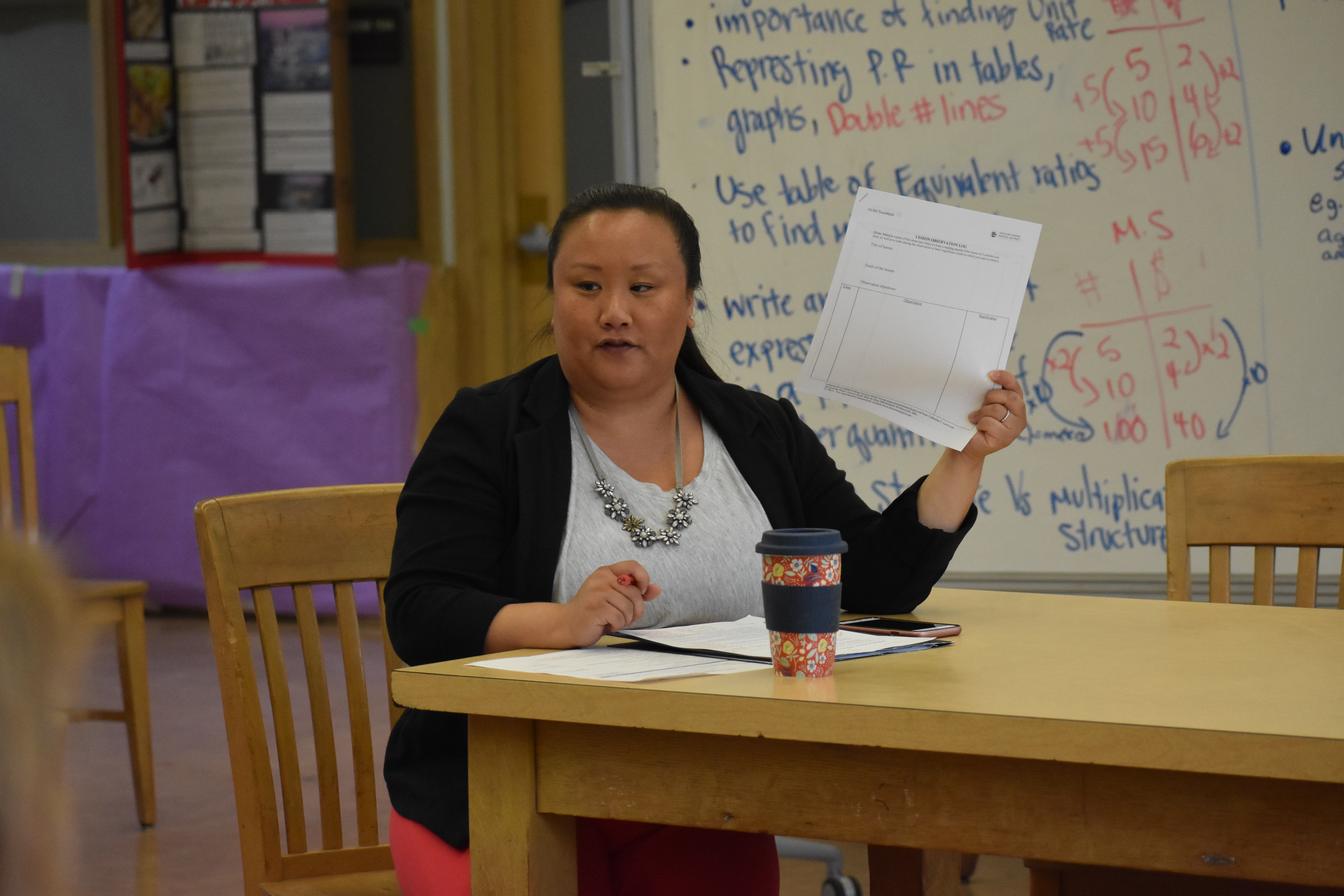 An elementary-age male student points while his female teacher stands beside him and observes