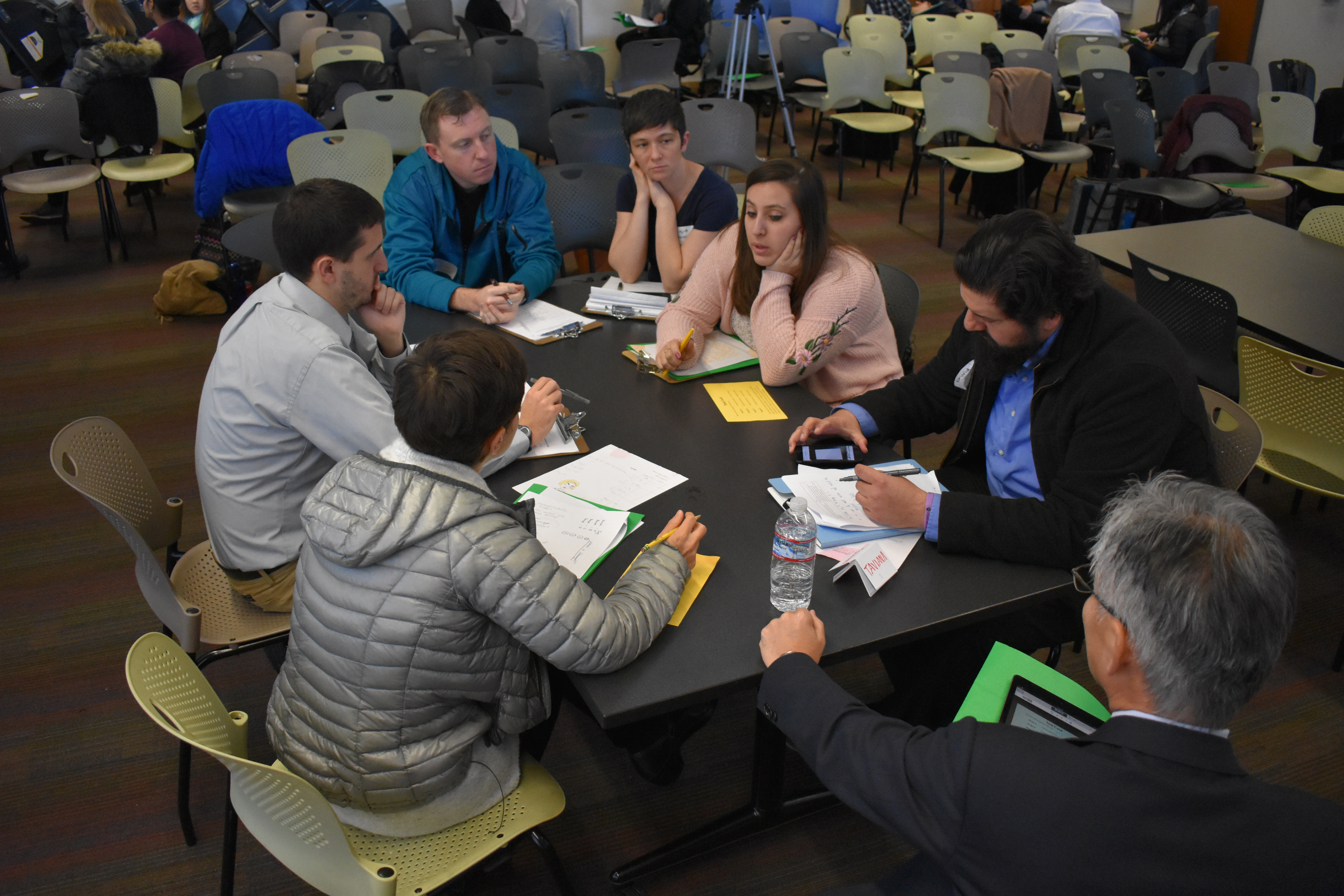 Seven teachers sit around table in discussion