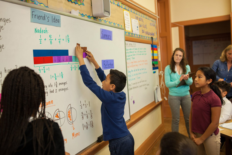 MG_0338_optimized An elementary-age male student points while his female teacher stands beside him and observes
