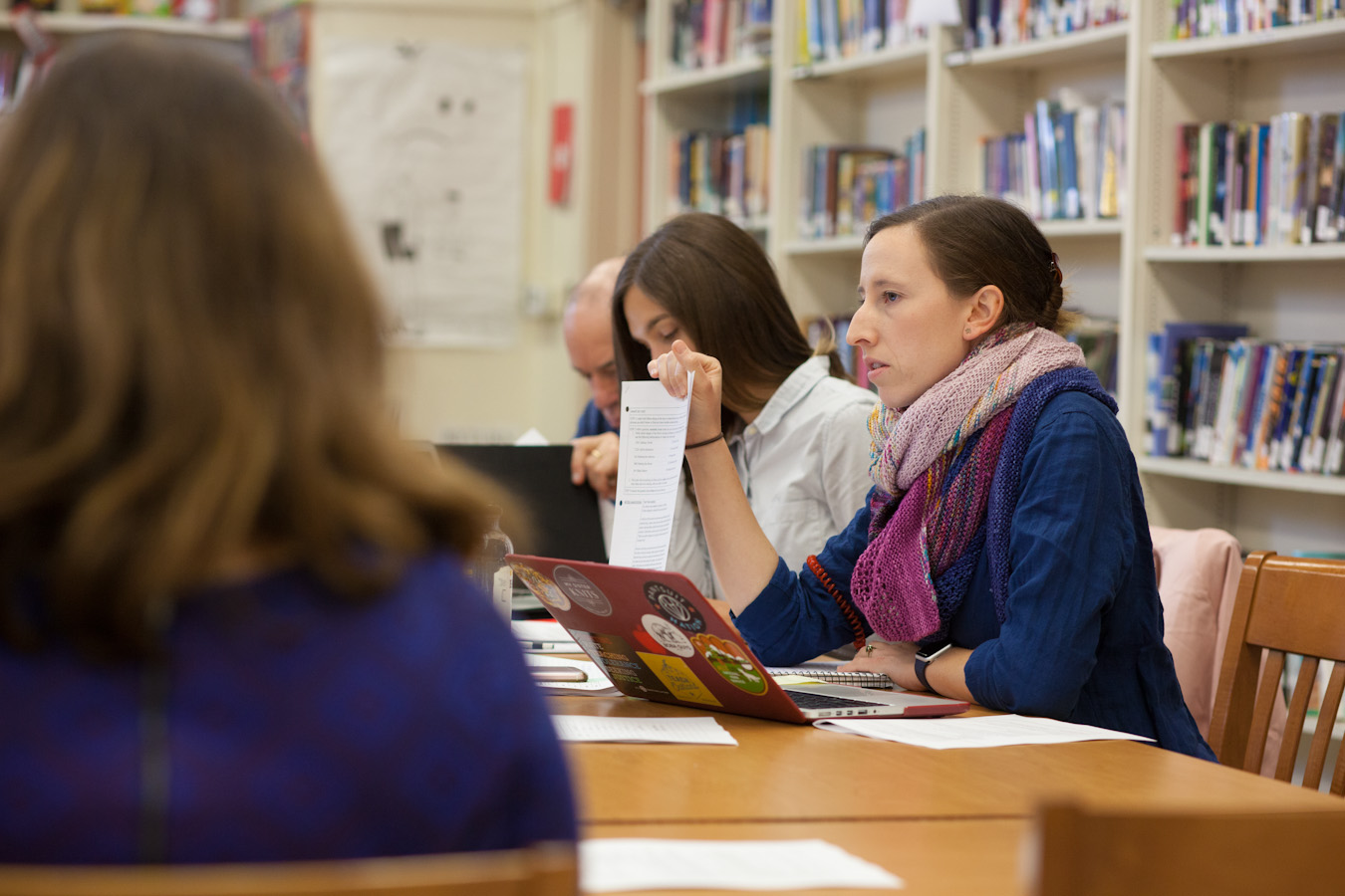 An elementary-age male student points while his female teacher stands beside him and observes
