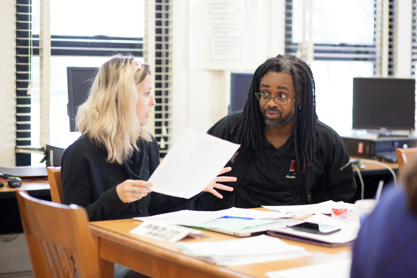 Two teachers discussing a paper that one of them is holding